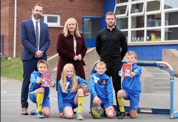 Education Minister praises ‘Books and Boots’ reading programme, along with Principal Ian McManus, coach Jamie Mulgrew and pupils.