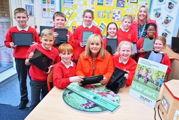 Photo of Michelle McIlveen with school children with their new digital devices.